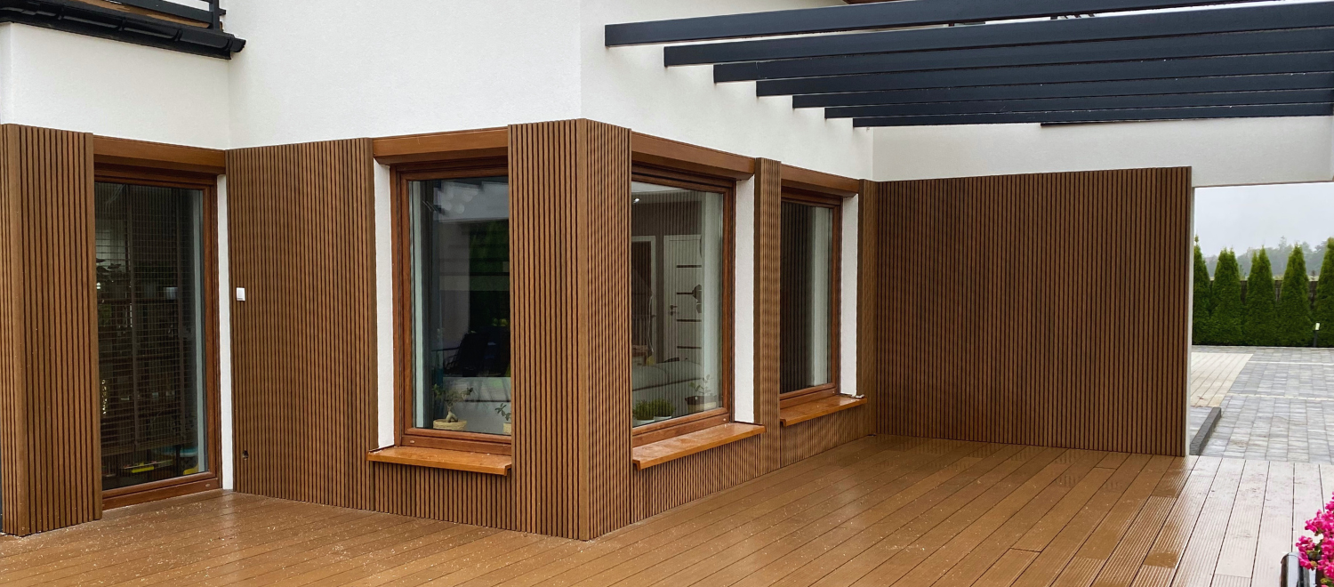 Nowoczesny taras z deską kompozytową i pionową elewacją.