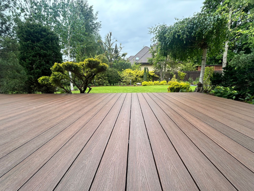 Taras w ogrodzie przy domu z brązowych desek kompozytowych marki Advance Naturale